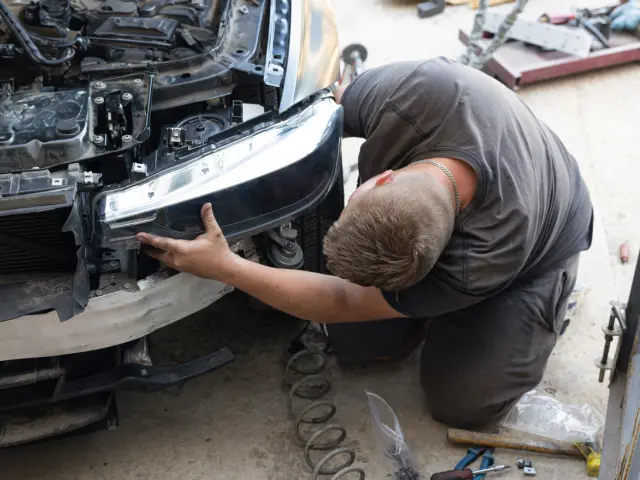 Mecánico cambia un faro del coche.