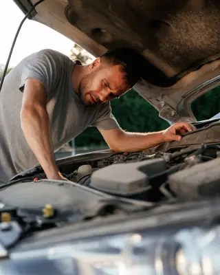 Un hombre intenta reparar su coche.