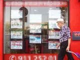 Un hombre camina frente al escaparate de una agencia inmobiliaria en Madrid.