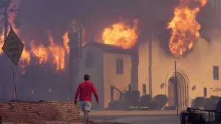 FILE - A man walks in front of the burning Altadena Community Church, Wednesday, Jan. 8, 2025, in the downtown Altadena section of Pasadena, Calif. (AP Photo/Chris Pizzello, File)