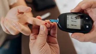 Una enfermera mide el nivel de glucosa en sangre de una paciente