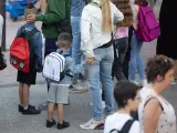 Varios niños esperan para entrar al colegio el primer día del curso escolar.